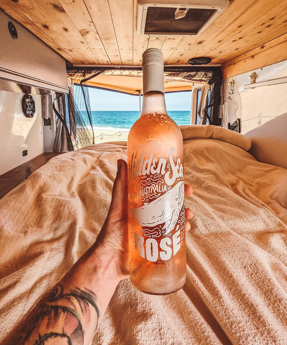 a hand hold a bottle of rose wine inside a van.
