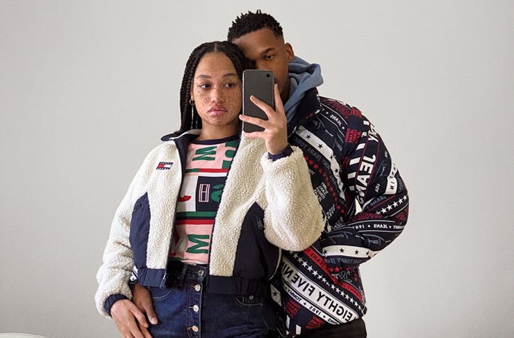 two people standing in front of mirror wearing tommy jeans gear taking a photo with a phone